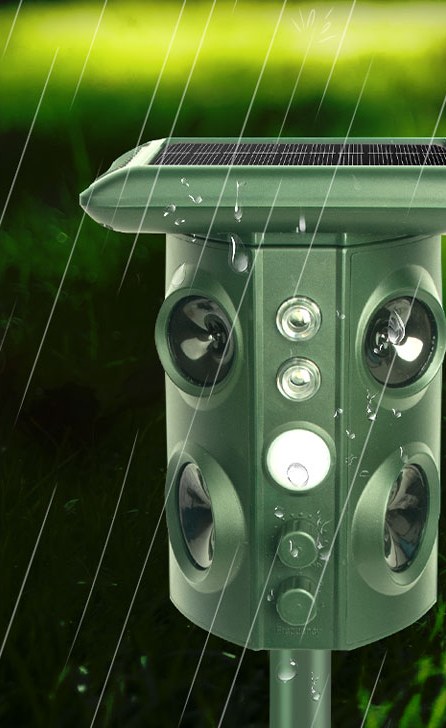 The repeller standing in heavy rain on a lawn, water beading on the housing